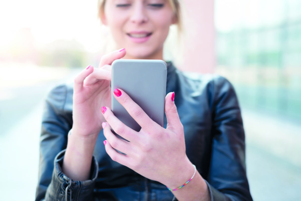 Young girl texting and using smart phone in the city